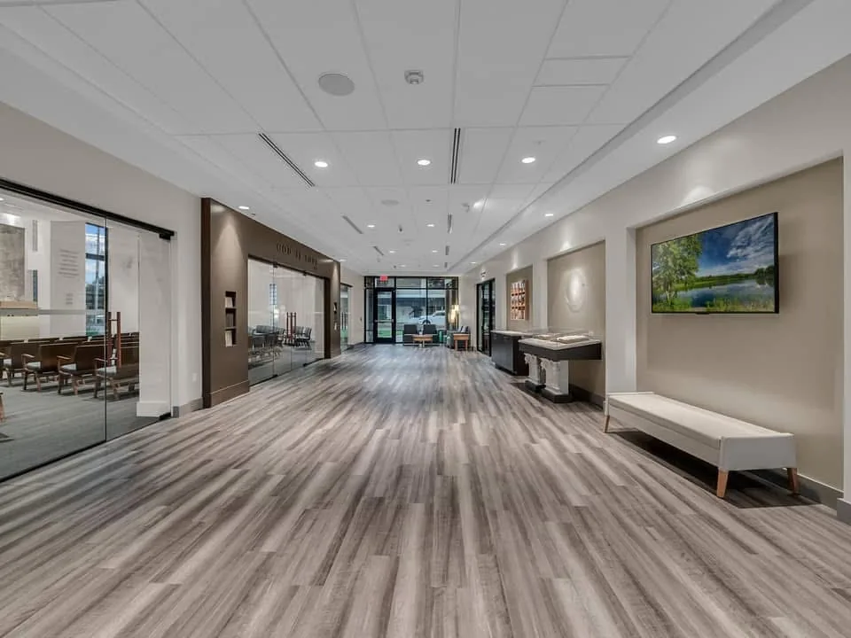 Long hall with recessed wall areas, a ceiling with acoustical panels and wood-look flooring.